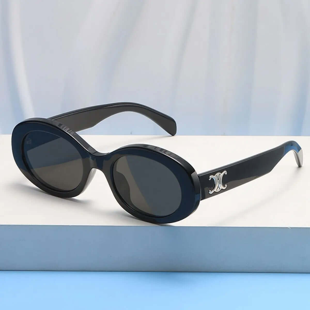 Oval Frame Fashion Sunglasses on a display table with a stylish design and UV protection.