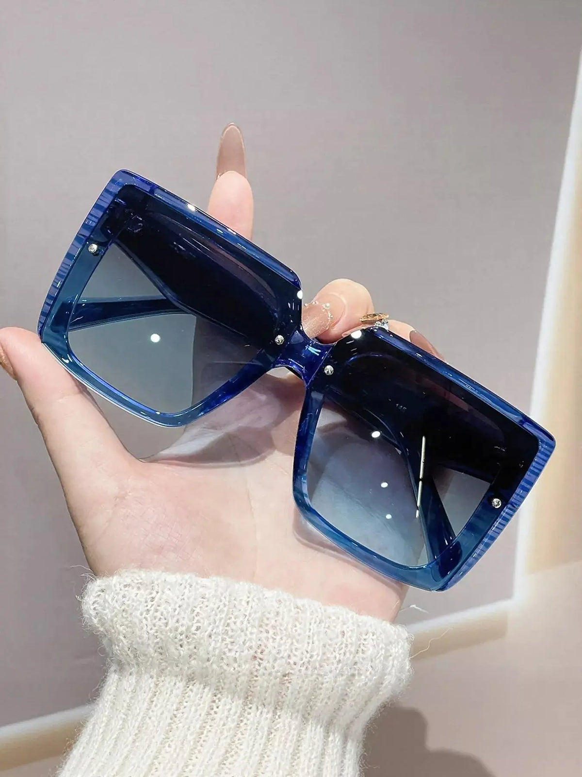 Oversized Gradient Square Sunglasses held in hand with blue gradient lenses and polycarbonate frame.