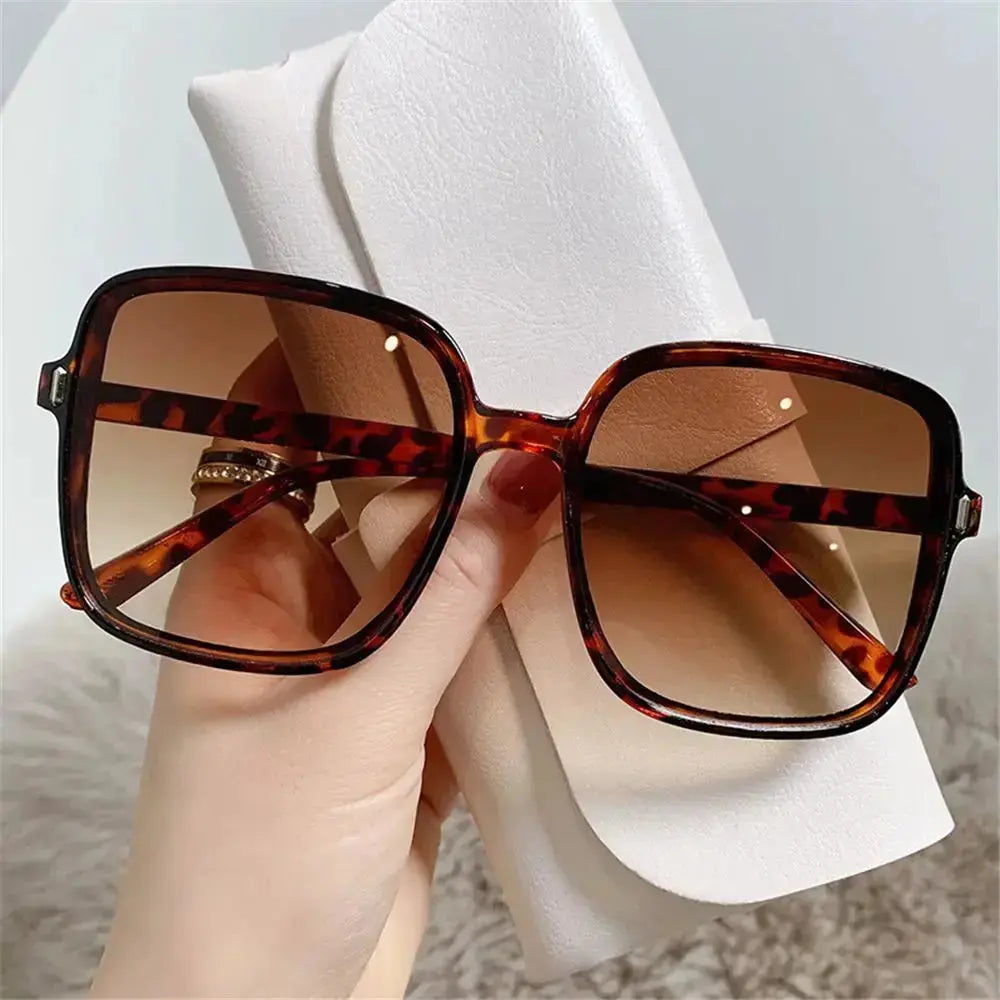 SquintProof Retro Rivet Small Frame Square Round Sunglasses in tortoiseshell design held with one hand.
