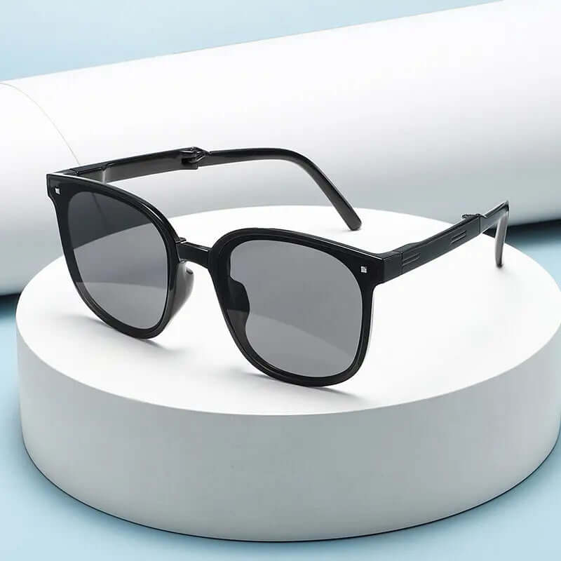 Lightweight Foldable Sunglasses displayed on a circular pedestal with a light blue background