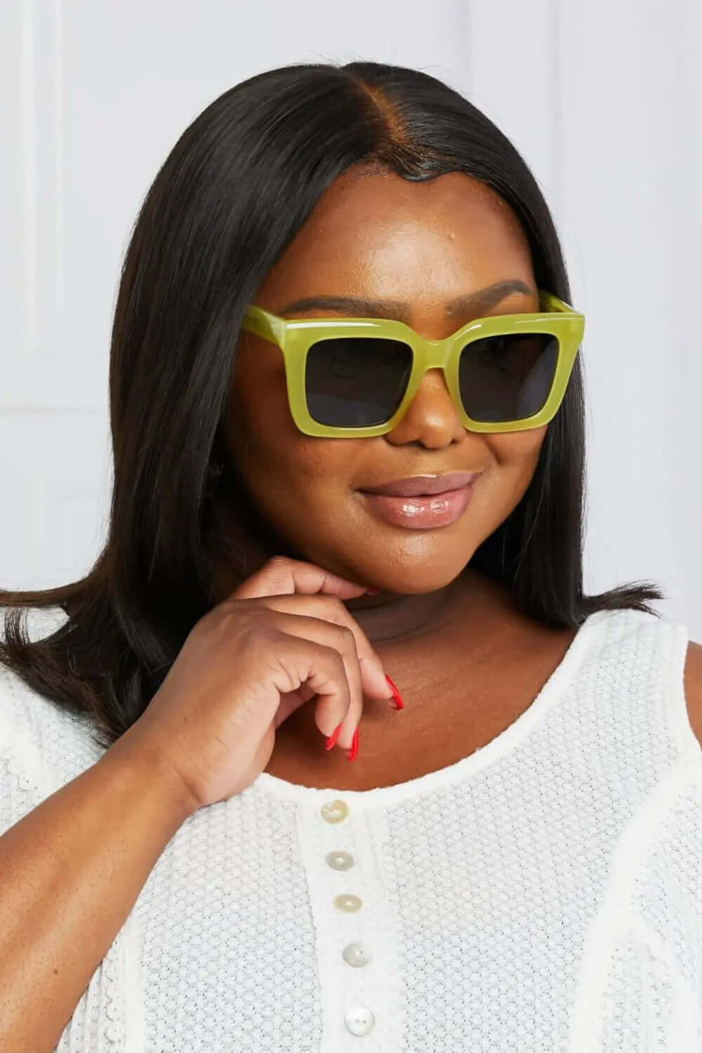 Stylish woman wearing square polarized sunglasses with a unique green frame.